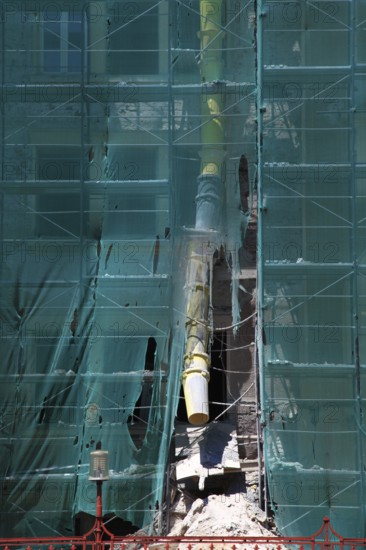 Construction site, house with scaffolding and a net in front of it as dust protection, waste tunnel