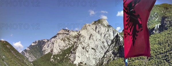 Mountain landscape with the Albanian flag against a clear sky and impressive rock formations, Peaks