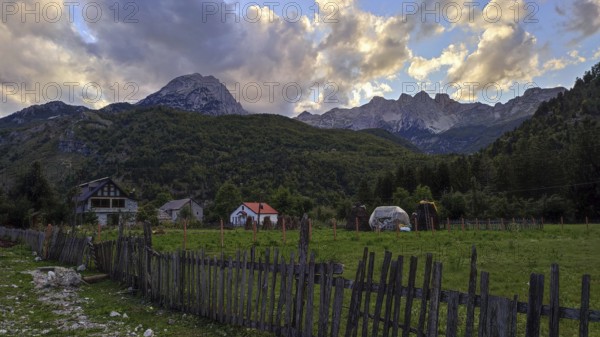 Idyllic farm against a dramatic mountain backdrop in the warm light of sunset, Peaks of the