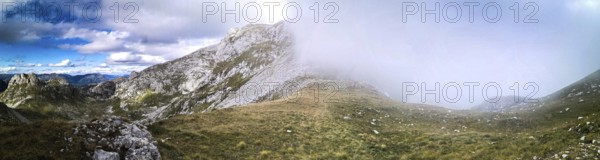 Panorama of a mountain landscape with fog moving over the hills and contrasting the sky, Peaks of