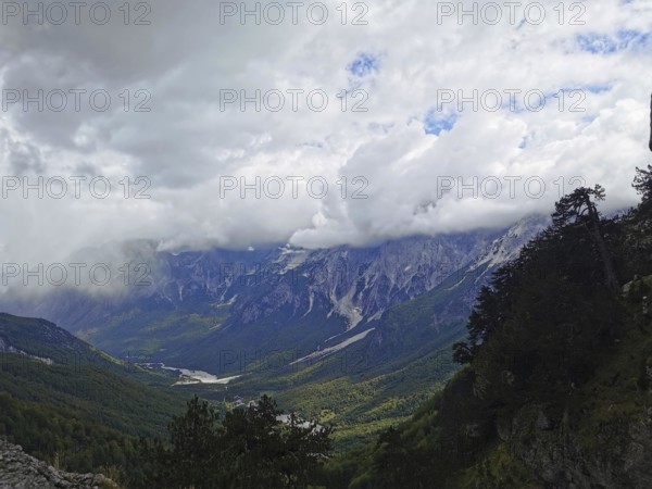 Dramatic cloud cover over a wide valley and towering mountains, Peaks of the Balkans, hiking in the