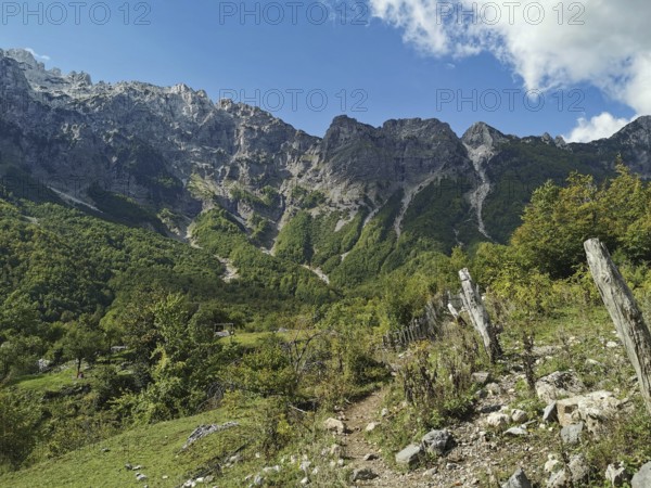 Mountainous area with fences and a hiking trail under a clear sky, Peaks of the Balkans, hiking in