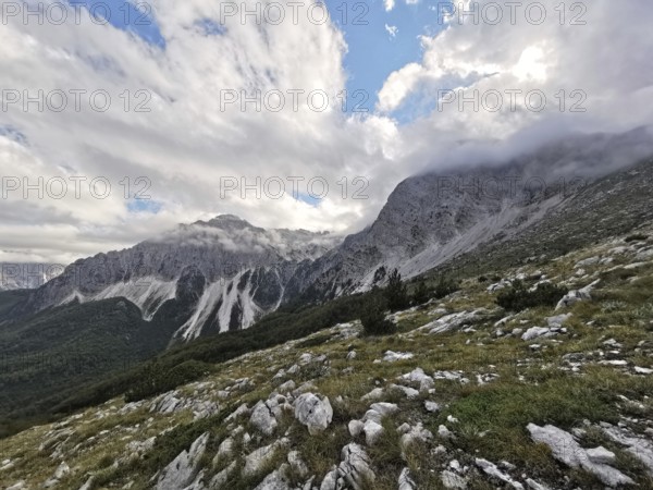 View of a mountainous landscape with dramatic clouds and rocks in the foreground, Peaks of the