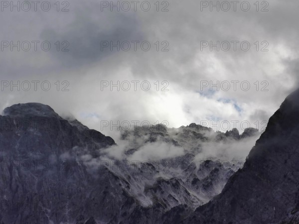 Dramatic cloud formations over rocky mountain peaks, mostly in shades of gray, Peaks of the