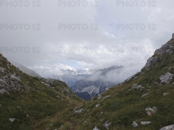 Snowy valley surrounded by mountains, partly obscured by clouds and fog, Peaks of the Balkans,
