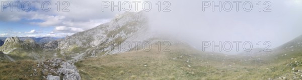 Mountain landscape with fog that partially obscures the view, under a changing sky, Peaks of the