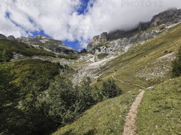 Trail through a mountainous landscape with dramatic clouds in the sky, Peaks of the Balkans, hiking
