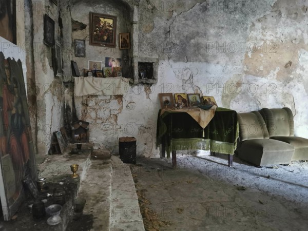 Atmospheric interior view of an abandoned Orthodox chapel with icons and dilapidated walls, Himare,