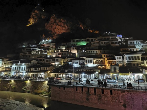 Night view of an illuminated city on the slope of a hill with river in the foreground, Berat,