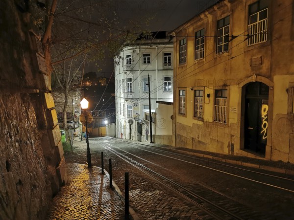 Night view of a picturesque street with cobblestones and buildings illuminated by lamps, tracks of