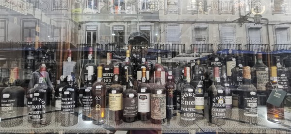 Old port wine, wine bottles and spirits in a shop window with city reflections in the background,