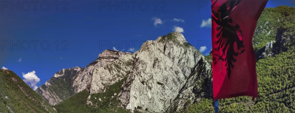 Alpine landscape with an Albanian flag and majestic mountains under blue sky, Peaks of the Balkans,