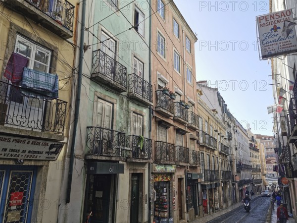 View of a street with colorful buildings, laundry hanging on wrought iron balconies in Lisbon, Old