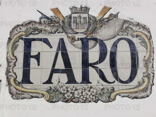 Artfully designed tile painting with Faro lettering and a coat of arms on a wall, Faro, Algarve,