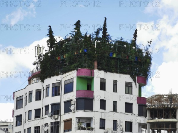Modern building with green roof garden and colorful building elements, jungle on the roof, urban