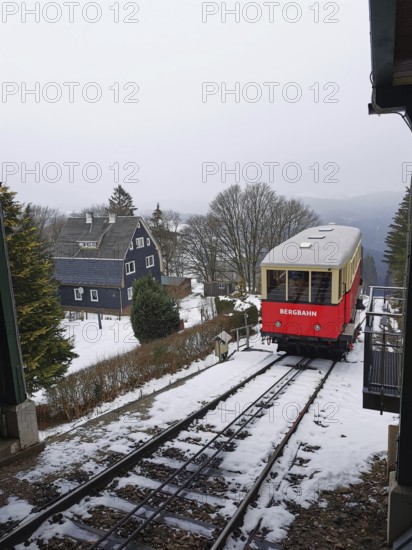 Red train goes through snow-covered mountain landscape, Oberweissbach cable car, Rennsteig,