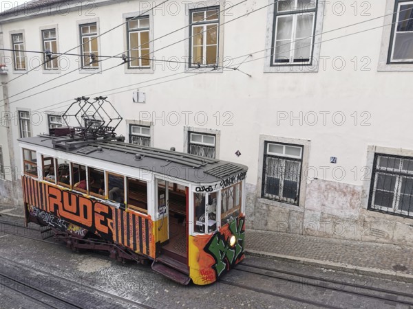 Historic funicular, Elevador da Gloria with colorful graffiti goes down a steep road, Lisbon,