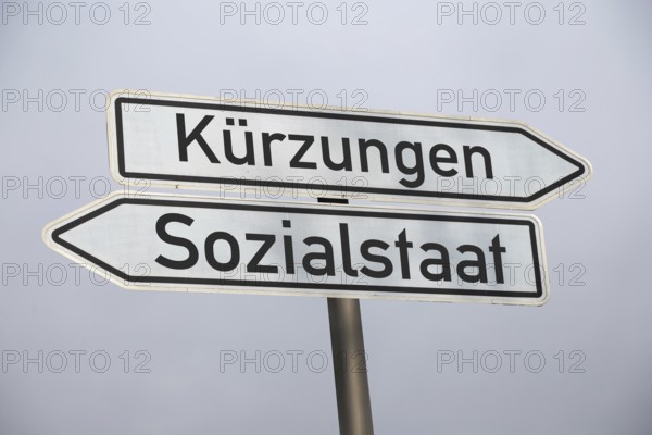 (photo montage) Directional arrows against a grey sky point in the directions of CUTS and WELFARE