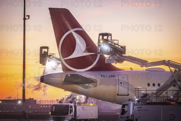 Frost at the airport in front of sunrise. A Turkish Airways aircraft is de-iced. Airbus A321-231.