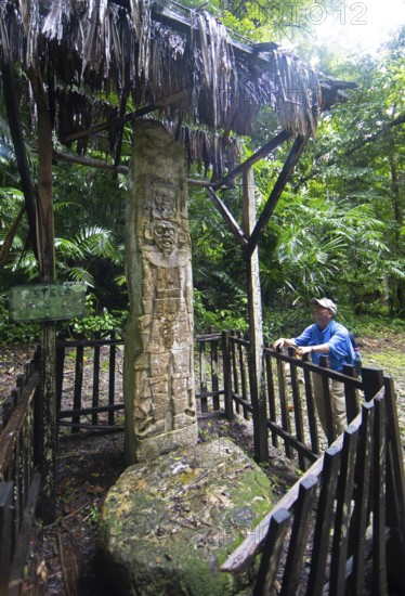 Guatemalan man from the Mayan people looks at a hieroglyphic stele in the Seibal or El Ceibal