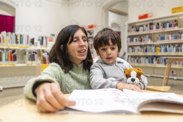 Mother and young son enjoying quiet time together in a public library, actively participating in a