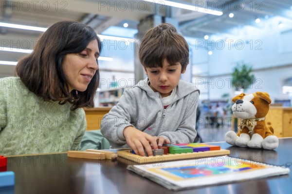 Teacher and young boy engaging in educational play, carefully fitting colorful geometric blocks