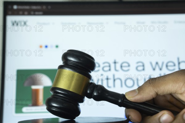 Dhaka, Bangladesh- 20 June 2025: A hand holds a gavel in front of a computer screen displaying