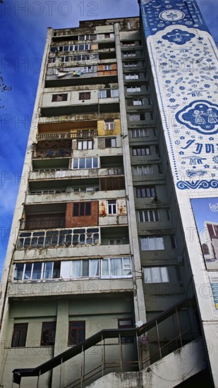 The colorful façade with windows, balconies, laundry, of a tall, old, partly dilapidated