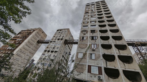 Three high-rise buildings connected by metal bridges under cloudy skies, nostalgic charm,