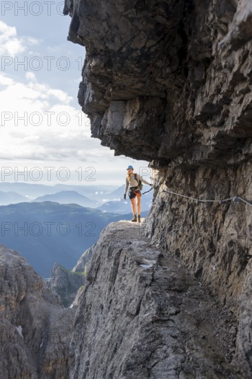 Climbers on a rock band, Bocchette Centrale band trail, via ferrata in the Brenta Mountains,