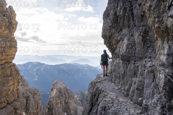 Climbers on a rock band, Bocchette Centrale band trail, via ferrata in the Brenta Mountains,