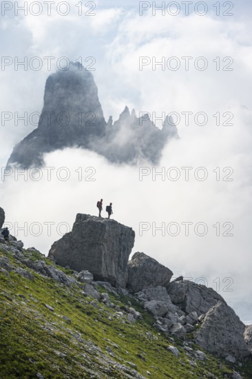 Alpine panorama, mountaineers on a large rock, fog and Torre Di Brentai and Cima Tosa, rocky