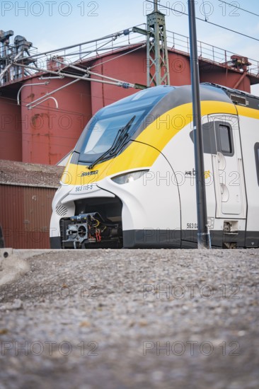 Modern locomotive on rails against an industrial backdrop under grey skies, opening of the Hermann