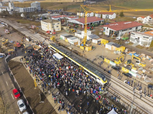People gather around a train on a construction site, aerial view with landscape in the background,