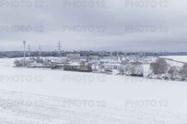 A wide snowy field with power lines and a substation in the distance, substation, Jettingen,