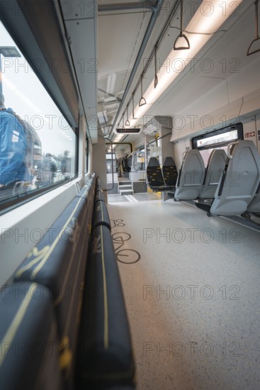 Interior view of a modern train with windows and folding seats, Siemens Micro Plus B battery