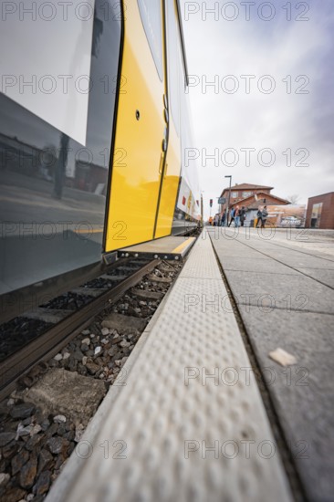 Close-up of a yellow train on a railroad track with focus on the rails, battery electric train