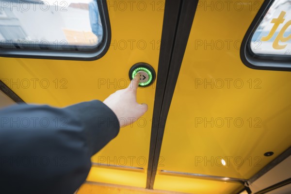 Hand presses button on yellow train door, surrounded by windows, battery electric train Siemens