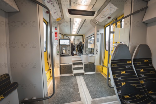 Interior of a modern train with grey and yellow elements and vacant seats, Siemens Micro Plus B