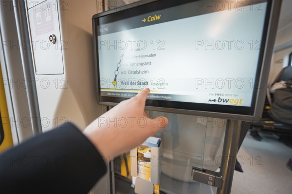 Display screen with timetable and hand showing departure time, battery electric train Siemens Micro