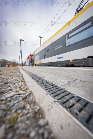 Person walking next to a modern yellow train on the platform, Siemens Micro Plus B battery electric