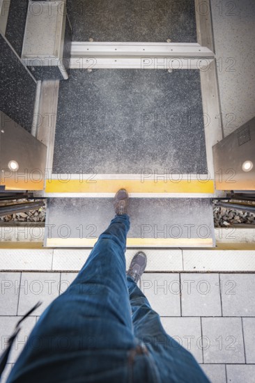 View from above of a passenger crossing the platform. A dynamic perspective with concrete paving,