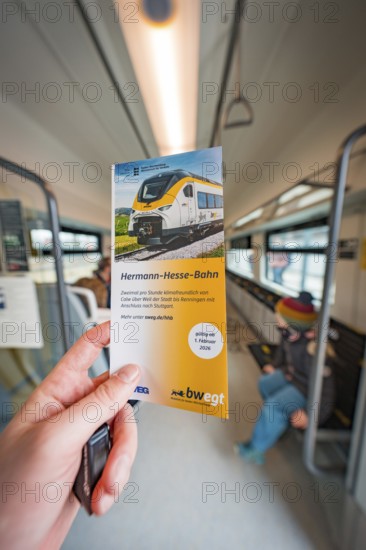 Hand holding brochure about the Hermann-Hesse railway inside the train, battery electric train