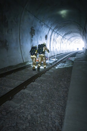 Firefighters in protective suits walk through a dark tunnel on tracks, fire drill on the Hermann
