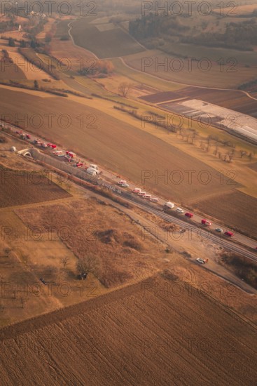 Emergency vehicle convoy on country road in vast, hilly landscape at dusk, fire drills on the