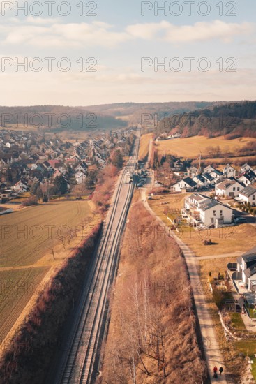 Aerial view of a village with railroad tracks surrounded by fields and hills, fire drill on the