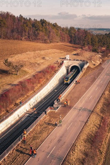 Train leaves a railway tunnel surrounded by emergency services and surrounding countryside, fire