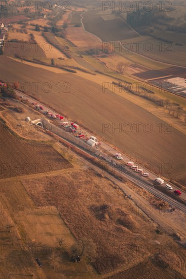 Long row of emergency vehicles on country road with extensive landscape views at dusk, fire drill