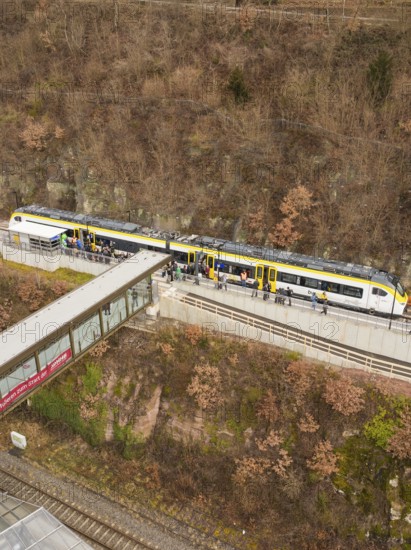 Train at a train station along a hill with bare trees and people waiting, opening of the Hermann
