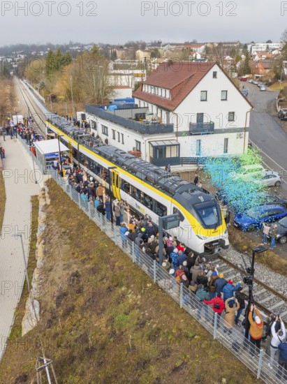 Regional train at a station event with crowds and rain of confetti in a city environment, opening